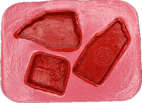 a mold with three pieces of red plastic in it